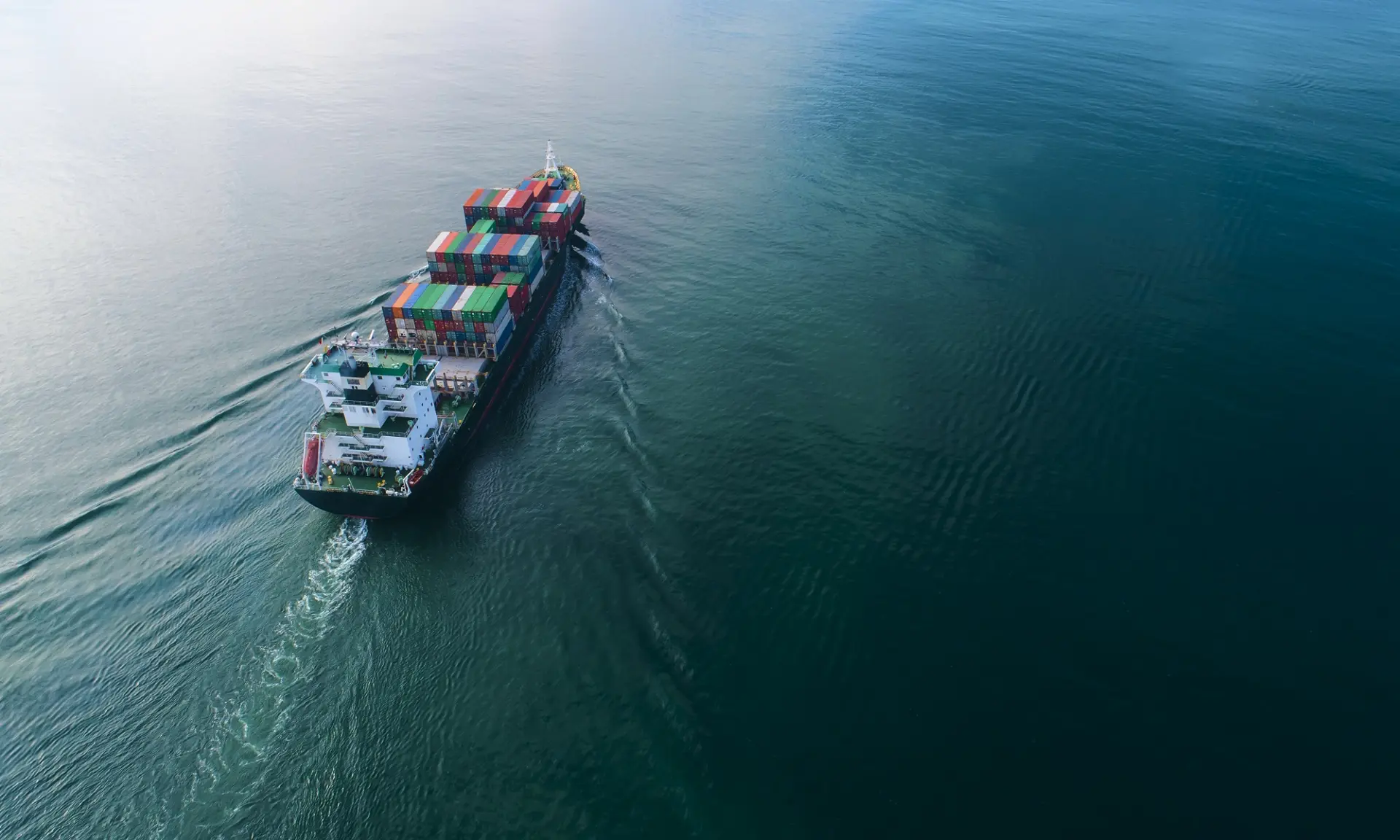 Aerial view of a container ship under way across open ocean.